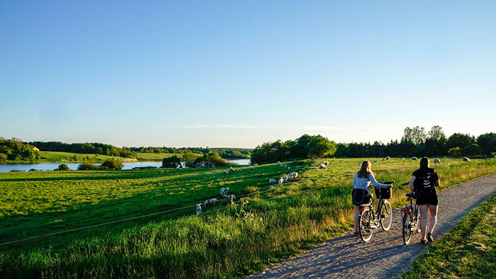 Billede viser to personer der går med cykler i naturen