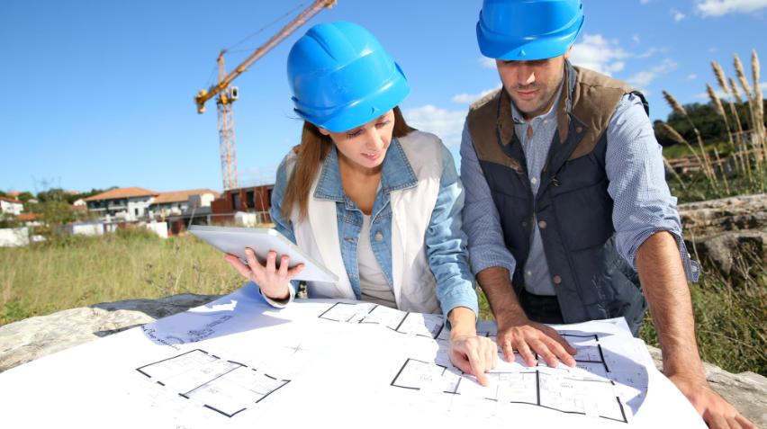 Billedet viser to byggeleder som kigger på byggetegning 