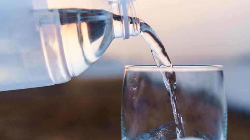 Billedet viser en person der drikker vand af en rindende vandhane.