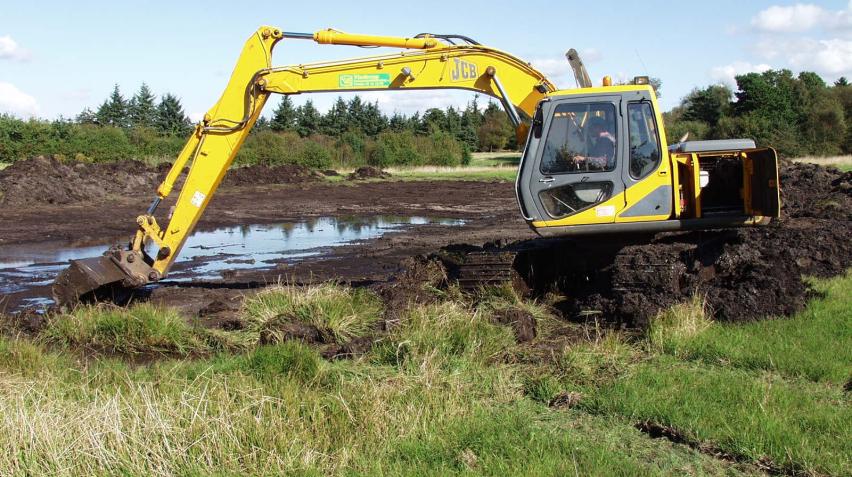 Udgravning af vandhul med en stor gravmaskine på en mark