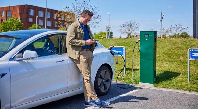 Mand der står og venter mens elbil er til opladning