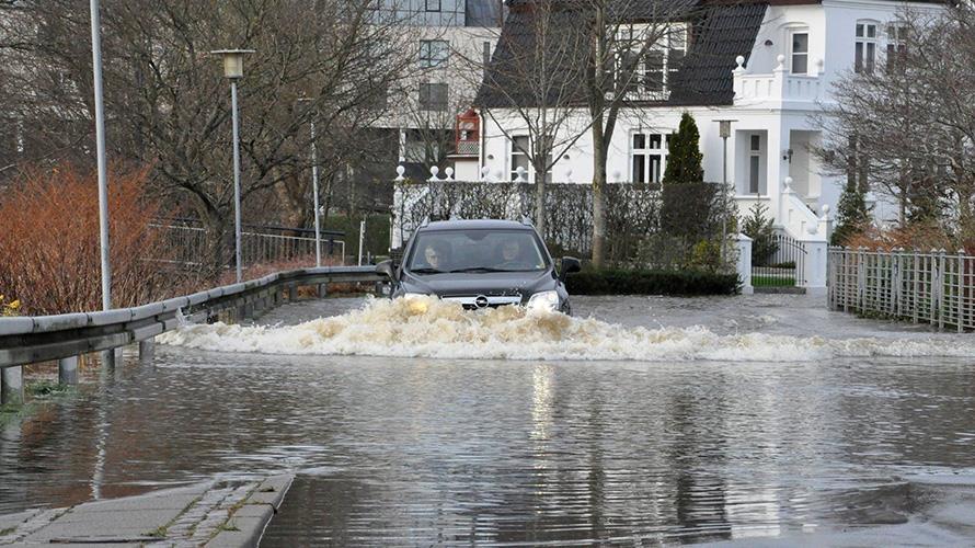 En bil kører på oversvømmet vej i Holstebro